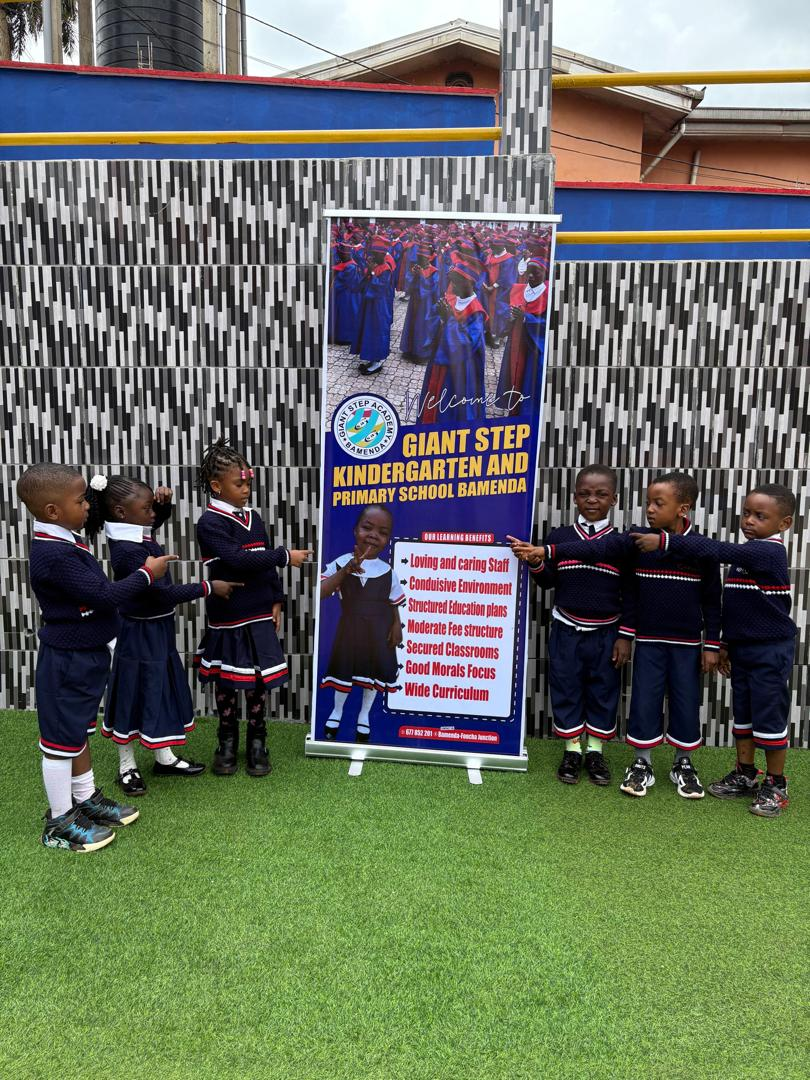 Nursery pupils in uniform beside the school welcome banner