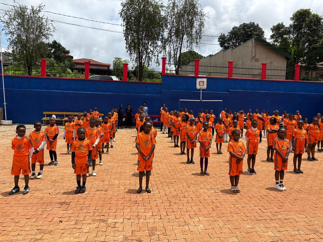 Pupils in orange sports kit lined up on the school yard